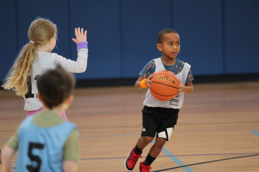 Little boy playing playing a basketball game with other kids