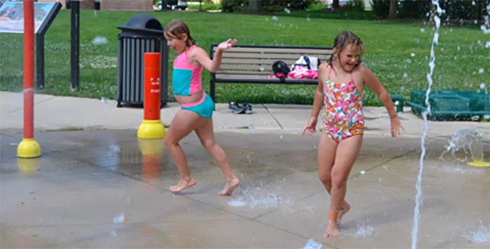 Two girls playing in the water at the splash pad